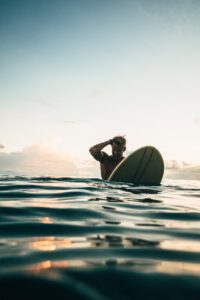 man holding white surfboard dawn patrol